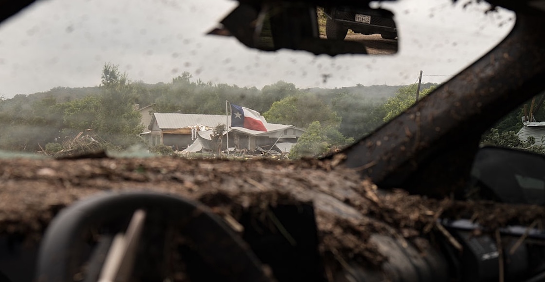 HUNT, TEXAS - JULY 05: A Texas flag is visible through the remnants of a vehicle destroyed by flood waters from the Guadalupe River on July 5, 2025 near Hunt, Texas. Heavy rainfall caused flooding along the Guadalupe River in central Texas with multiple fatalities reported. (Photo by Eric Vryn/Getty Images)